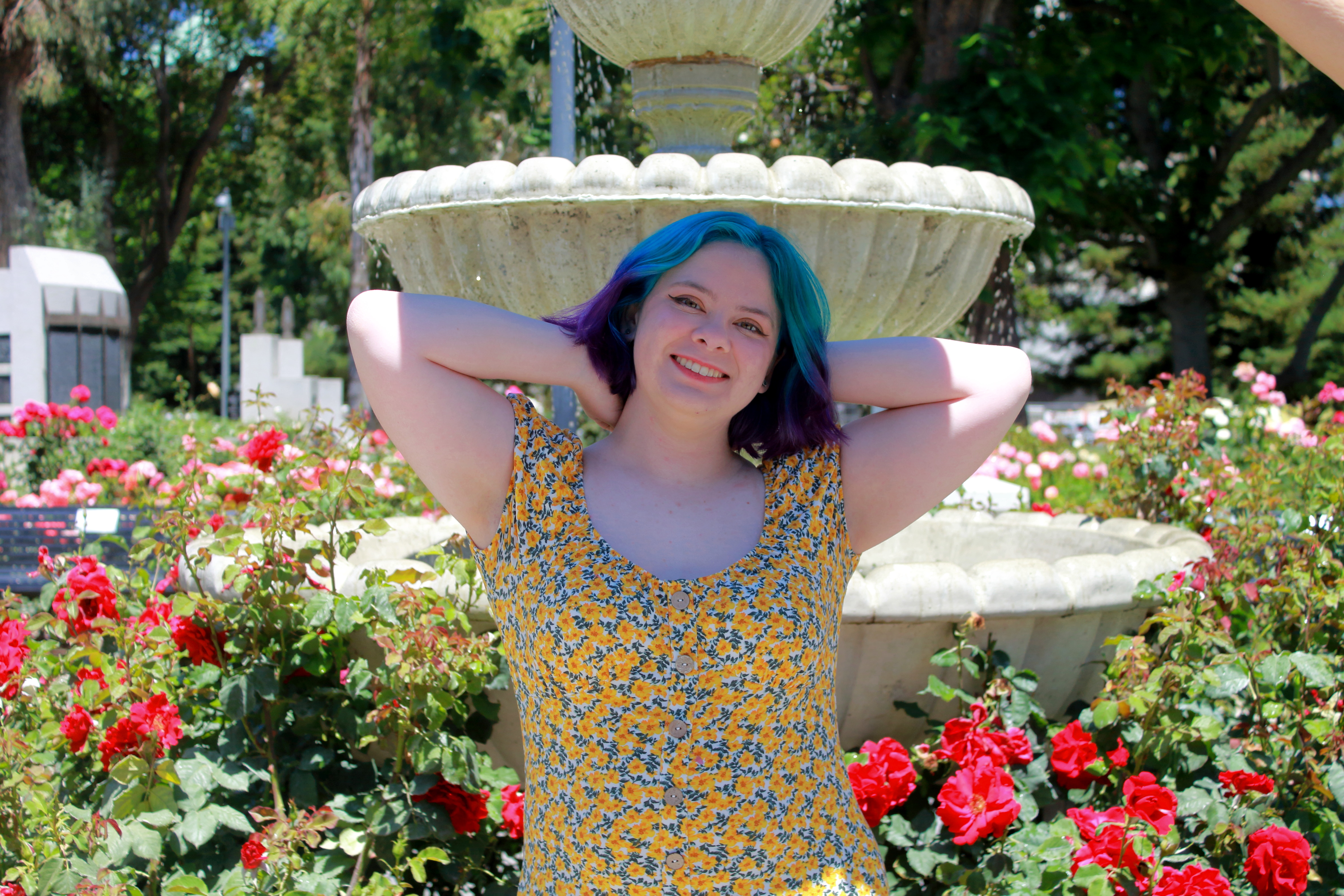 Girl posed in front of a fountain amidst a garden